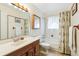 Bright bathroom with single sink, wood vanity, shower-tub combination, and tile floors at 7503 Saulsbury St, Arvada, CO 80003