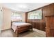 Bedroom features wood panel accent wall, carpet flooring, and two bright windows at 7503 Saulsbury St, Arvada, CO 80003