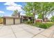 Brick home featuring an attached two-car garage, long driveway, manicured lawn, and mature trees at 7503 Saulsbury St, Arvada, CO 80003