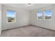Bright bedroom with neutral carpet, two windows with neighborhood views, and fresh, clean walls at 9479 Rifle St, Commerce City, CO 80022