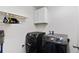Laundry room with modern black Samsung washer and dryer and overhead shelf and cabinet storage at 9479 Rifle St, Commerce City, CO 80022