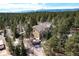 Aerial view of the home nestled among tall evergreen trees with beautiful snow-capped mountains in the distance at 19375 Sherwood Trl, Monument, CO 80132