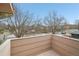 Outdoor balcony featuring wood floors with a light-colored wood plank railing and views of trees and a street at 925 Elm St, Denver, CO 80220