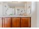 Bathroom vanity with cabinets and beige walls, featuring decor and white towels at 13360 W 83Rd Pl, Arvada, CO 80005