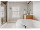 Bright bathroom featuring a soaking tub, glass shower, large window, and vanity at 13360 W 83Rd Pl, Arvada, CO 80005