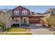 Charming two-story red home with a landscaped yard, covered porch, and attached two car garage at 13360 W 83Rd Pl, Arvada, CO 80005
