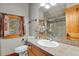 Bathroom features a tile countertop, wood cabinetry, and a shower with glass door at 8905 Carol Ln, Conifer, CO 80433