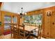 Dining room with a wooden table and chairs, surrounded by rustic wooden walls and windows at 8905 Carol Ln, Conifer, CO 80433