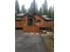 Inviting log home featuring a stone chimney and a large deck with a welcoming front entry at 8905 Carol Ln, Conifer, CO 80433