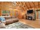 Living room with a stone fireplace, wooden walls, and comfortable furniture set at 8905 Carol Ln, Conifer, CO 80433