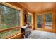 Cozy sunroom with wood paneling and multiple windows offering views of the surrounding trees at 8905 Carol Ln, Conifer, CO 80433