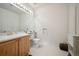 Bright bathroom featuring a large mirror, wood cabinets, and white tile flooring at 10520 W Vassar Dr, Lakewood, CO 80227