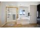 Bright bathroom featuring a bathtub, a shower with gold trim, and a sunny window at 10520 W Vassar Dr, Lakewood, CO 80227
