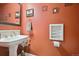 Stylish half bath with an ornate mirror, pedestal sink, and decorative accents with unique orange walls at 10520 W Vassar Dr, Lakewood, CO 80227