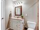 Well-lit bathroom with a single sink vanity, decorative mirror, and standard toilet at 17806 Coral Burst St, Parker, CO 80134