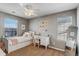 Bright bedroom with decorative string lights, white furniture, a ceiling fan and two large windows at 17806 Coral Burst St, Parker, CO 80134