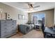 Bedroom with a ceiling fan, gray furniture, and decorative wall art, lit by natural light from a large window at 17806 Coral Burst St, Parker, CO 80134