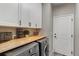 Efficient laundry room with front-loading washer and dryer, butcher block countertop, and white cabinets at 17806 Coral Burst St, Parker, CO 80134