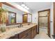 Bathroom featuring double vanity, granite countertop, and wood cabinets with views out the window at 5414 Golden Currant Way, Parker, CO 80134