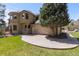 A beautiful home exterior with a stone patio and lush green lawn and mature tree at 5414 Golden Currant Way, Parker, CO 80134