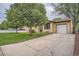 Home featuring a long driveway leading to a one car garage and mature shade trees in the front yard at 7618 Umatilla St, Denver, CO 80221