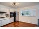 Bright kitchen featuring white cabinets, stainless steel refrigerator, and hardwood floors at 7618 Umatilla St, Denver, CO 80221
