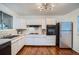 Bright kitchen featuring white cabinets, tiled countertops, and hardwood floors at 7618 Umatilla St, Denver, CO 80221