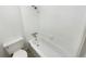 Bathroom with white tiled walls, shower over tub, and white toilet at 2401 S Gaylord St # 206, Denver, CO 80210