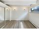 This bedroom has a closet with mirrored doors, new flooring, a window, and sconce lighting at 2401 S Gaylord St # 206, Denver, CO 80210