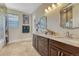 Bathroom with a double sink vanity featuring granite countertops, decorative mirrors, and tiled floors at 7343 Upton Ct, Castle Rock, CO 80104