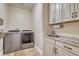 Laundry room featuring a sink, stone countertops, overhead cabinets, and modern appliances at 7343 Upton Ct, Castle Rock, CO 80104