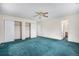 Spacious bedroom featuring plush teal carpet, ample closet space, and an ensuite bathroom at 15623 Degaulle Cir, Brighton, CO 80603