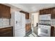 Kitchen features white appliances, tile floor, and wood cabinets at 15623 Degaulle Cir, Brighton, CO 80603