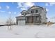 Two-story house with gray siding, stone accents, and a two-car garage in a snowy landscape at 25022 E 34Th Pl, Aurora, CO 80019