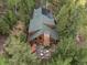 Aerial view of a log cabin nestled among lush trees, showcasing its roof and outdoor patio at 80 Spruce Ct, Evergreen, CO 80439