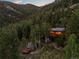 Secluded log cabin nestled in the forest, with solar panels and an outdoor deck at 80 Spruce Ct, Evergreen, CO 80439