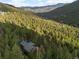 Scenic aerial view of a log home surrounded by dense forest and rolling hills at 80 Spruce Ct, Evergreen, CO 80439