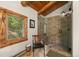 Bathroom featuring a glass shower, rustic wooden accents and a view of the trees at 80 Spruce Ct, Evergreen, CO 80439