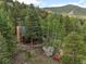 Log home blends with the natural landscape, showcasing an outdoor deck and stone chimney at 80 Spruce Ct, Evergreen, CO 80439