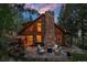 Charming log cabin with stone chimney and outdoor stone patio seating area at 80 Spruce Ct, Evergreen, CO 80439