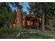 Charming log cabin features a stone chimney, outdoor patio, and well-maintained landscaping at 80 Spruce Ct, Evergreen, CO 80439