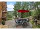 Outdoor patio with dining table, umbrella, and seating area surrounded by trees and mountain views at 80 Spruce Ct, Evergreen, CO 80439