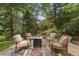 Secluded patio with stone tiling, a fire pit, and comfortable seating amidst lush trees at 80 Spruce Ct, Evergreen, CO 80439