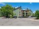 Multi-story condominium building with green siding and brick accents surrounded by a parking lot at 4899 S Dudley St # 7E, Littleton, CO 80123