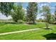 Expansive green space with mature trees and paved walkway under a beautiful, partly cloudy sky at 4899 S Dudley St # 7E, Littleton, CO 80123