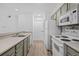 Well-lit kitchen featuring modern appliances, gray cabinets, and a stackable washer and dryer at 4899 S Dudley St # 7E, Littleton, CO 80123