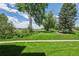 Lush green lawn featuring mature trees and landscaping, framed by a clear blue sky with scattered clouds at 4899 S Dudley St # 7E, Littleton, CO 80123