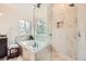 Luxurious bathroom with a soaking tub, a glass shower, and travertine tile at 176 S Rosemary St, Denver, CO 80230