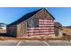 Rustic barn featuring a large American flag painted on its wooden exterior under a clear sky at 39167 Braxton Ln, Elizabeth, CO 80107