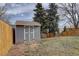 Backyard with lawn, fence, mature trees, and a wooden storage shed at 4542 S Quintero St, Aurora, CO 80015